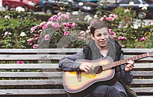 Young man playing on acoustic guitar outdoor