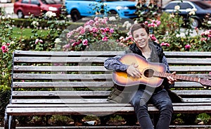 Young man playing on acoustic guitar outdoor