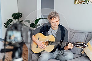 Young man playing acoustic guitar and recording music video for his social networks. Amatuer musician create content at