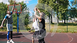 Young man playing basketball outdoors with friends, dribbling and missing the basket