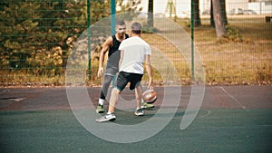 Young man playing basketball on the sports ground with friend - getting a score