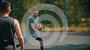 Young man playing basketball on the sports ground with friends - dribbling, avoiding his opponents