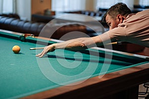 Young man playing billiard indoors. Spending free time on gambling.