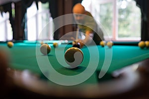 Young man playing billiard indoors. Spending free time on gambling