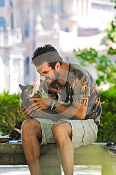 Young Man Playing With A Cat In Public Park