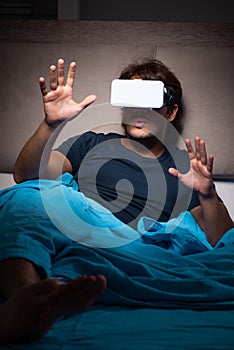 The young man playing computer games at night in bed