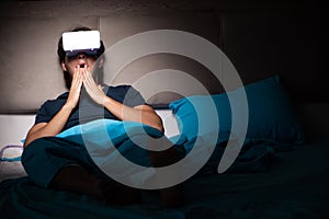 The young man playing computer games at night in bed