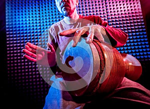 Young man playing on djembe in sound recording studio.