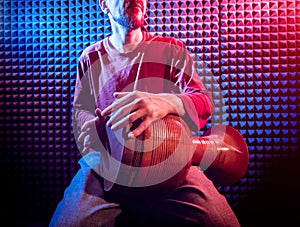 Young man playing on djembe in sound recording studio.