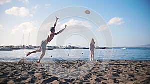 A young man playing frisbee on the beach with his girlfriend. Falling on the sand