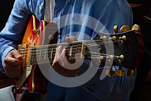 Young man playing guitar, close up view, dark background