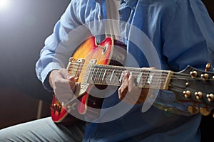 Young man playing guitar, close up view, dark background