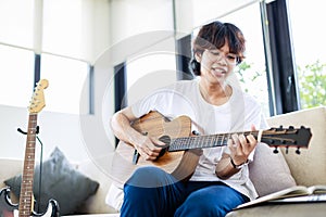 Young man playing guitar in living home at home, guitarist musician lifestyle