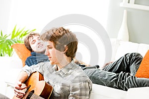 Young man playing guitar on the living room floor