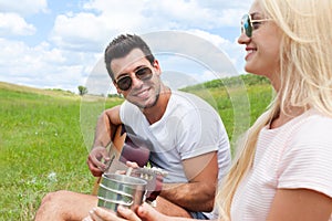 Young man playing guitar to his girl summer day couple