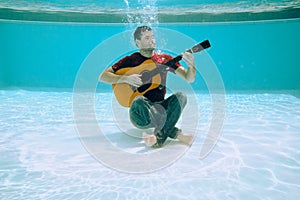 Young Man Playing Music With Guitar And Singing Song Underwater