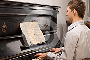 Young man playing music on a wooden piano