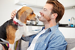 Young Man Playing With Pet Dog At Home