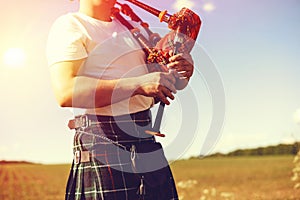 Young man playing pipes in national uniform on