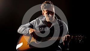 Young man playing romantic ballad on guitar, acoustic performance, concert photo