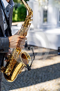 Young man playing the saxophone at the wedding. Blurred background. Selective focus.