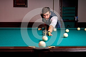 young man is playing snooker, he is aiming to shoot the snooker ball