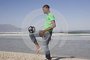 Young Man Playing Soccer On Beach