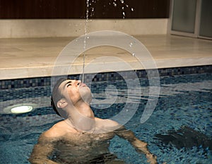 Young Man Playing in Swimming Pool, Spitting Water photo