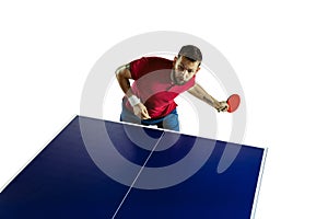 Young man playing table tennis on white studio background