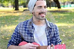 Young man playing the ukelele in a park.