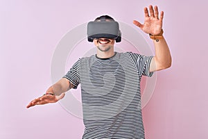Young man playing video game wearing virtual reality glasses, looking at virtual simulation amazed and smiling happy