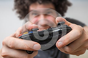 Young man is playing video games and holds joystick or controller