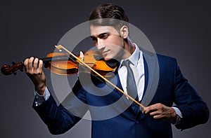 Young man playing violin in dark room