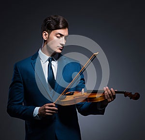 Young man playing violin in dark room