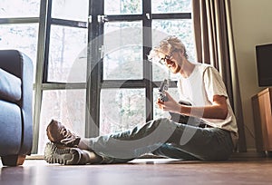 Young man plays on guitar sitting on the floor in living room