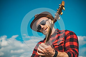 Young man plays guitar at sky.