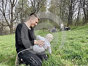 A young man plays with his baby nephew in the park on the grass