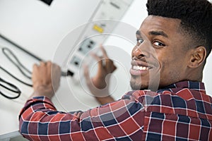 Young man plugging power cable into computer