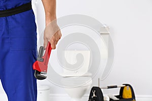 Young man with plumber wrench and toilet bowl