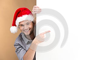 Young man pointing on blank panel on brown background.