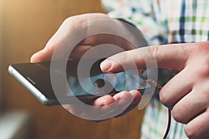 Young man pointing finger on smartphone screen, typing message or using app