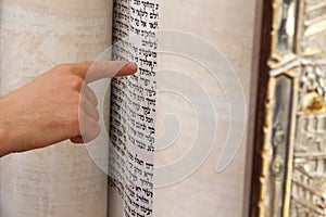 A young man pointing at a phrase in a bible book