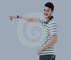 Young man pointing at something with his finger isolated on grey