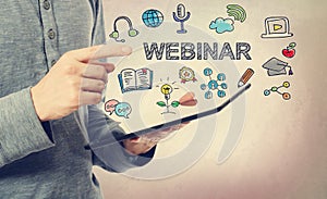 Young man pointing at Webinar concept over a tablet