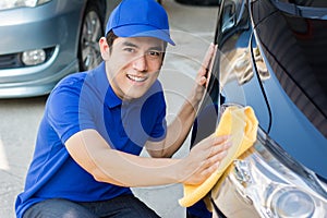 Young man polishing cleaning car with microfiber cloth photo