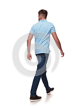 Young man in polo shirt walks and looks to side