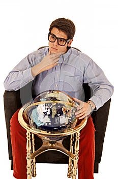 Young man pondering life with world globe in chair