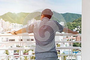 Young man is pondering on terrace of house roof against background of cityscape at sunset