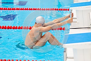 Young man in a pool - go to start swimming. backstroke during