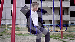 Young man in a poor state of health sits on a swing